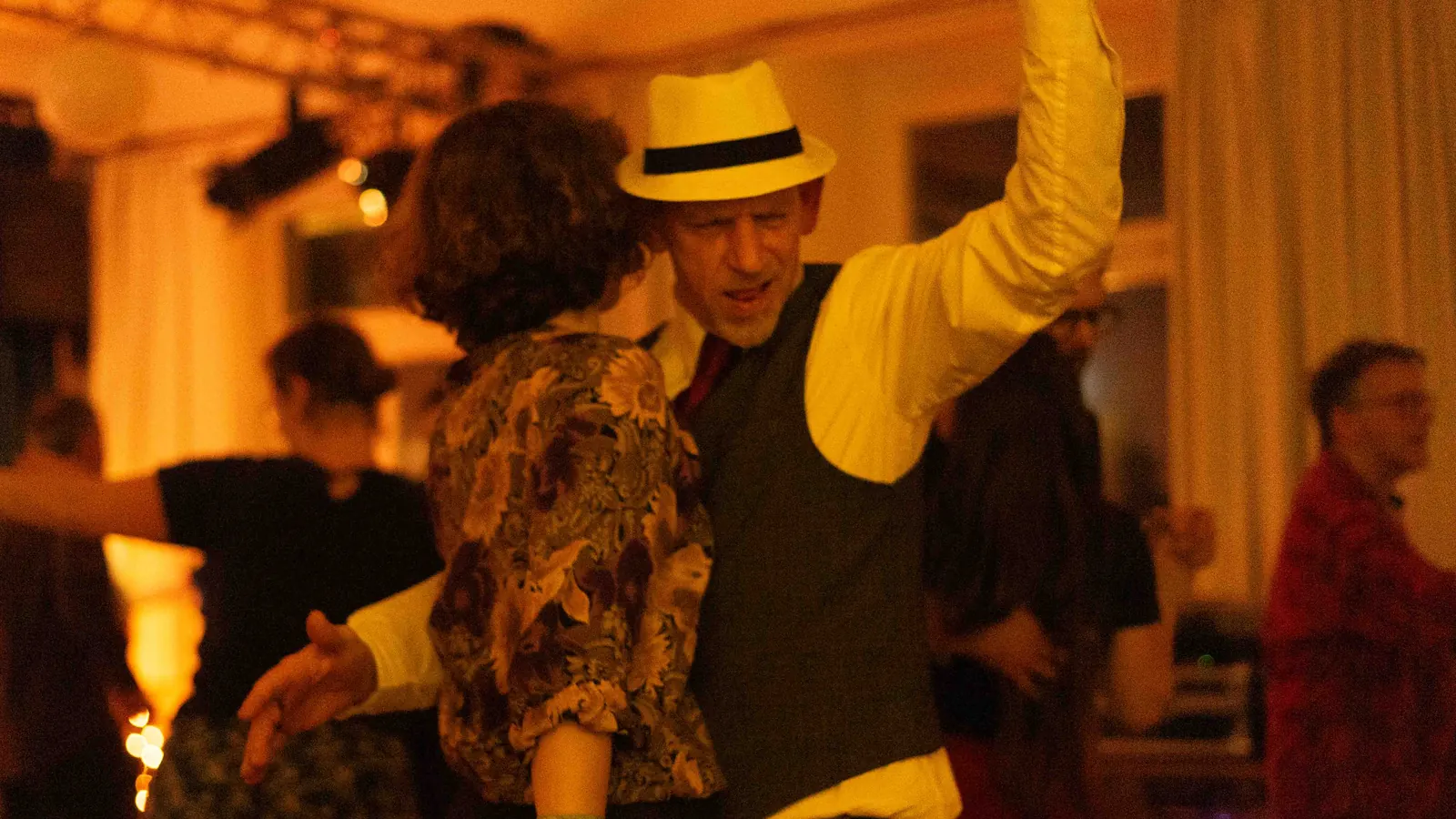 Ein Tänzer mit Strohhut reißt beim Swingtanzen mit seiner Partnerin auf einer Blue-Forest-Party die Arme hoch