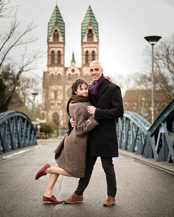 Die Lehrer Lidia & Fernando posieren auf der Blauen Brücke in Freiburg vor der Herz-Jesu-Kirche