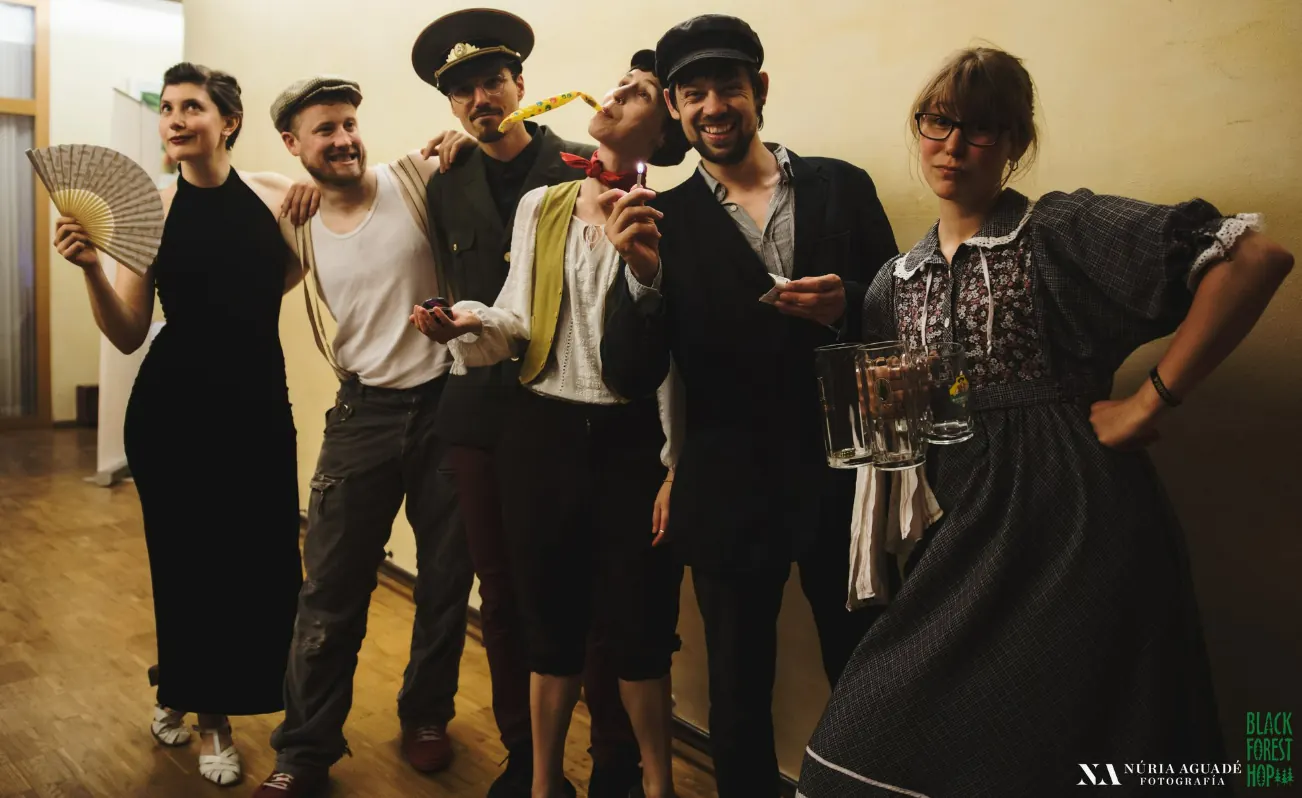 Team und Performer posieren in Kostümen der 1920er und 1930er Jahre mit Fächer, Mützen und Bierkrügen