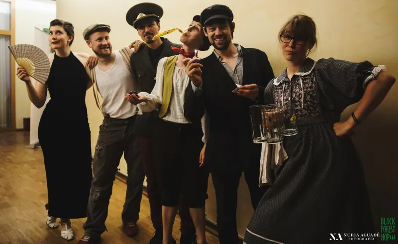 Team und Performer posieren in Kostümen der 1920er und 1930er Jahre mit Fächer, Mützen und Bierkrügen